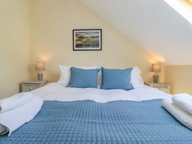 A bedroom with a bed with blue cushions and a quilt with bedside tables and lamps at Primrose Cottage in Ambleside