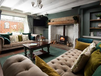 A living room with two sofas a wooden coffee table and a fireplace at Owl Cottage in Morpeth