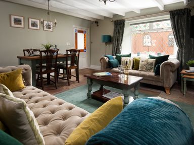 A living room with two sofas a coffee table dining table with chairs and a large window at Owl Cottage in Morpeth