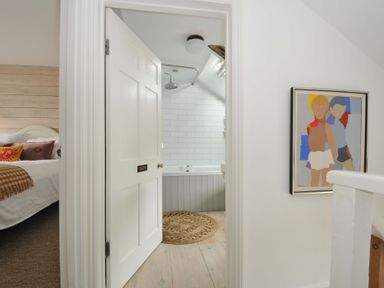 A bathroom with a bathtub visible through a door at Island House Golant near Tywardreath