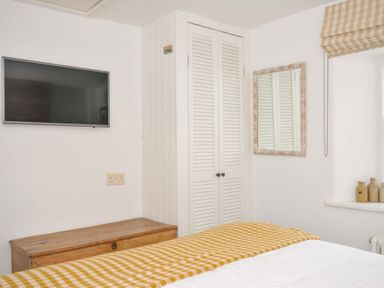 A bedroom with a television and wardrobe at Island House in Golant near Tywardreath
