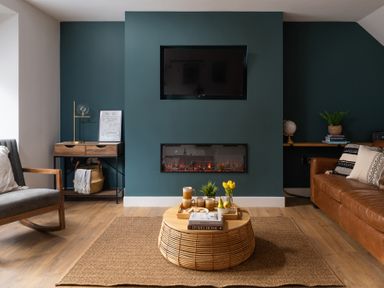 A living room with a mounted TV and electric fireplace a rocking chair and a brown leather sofa at Hebog in Beddgelert