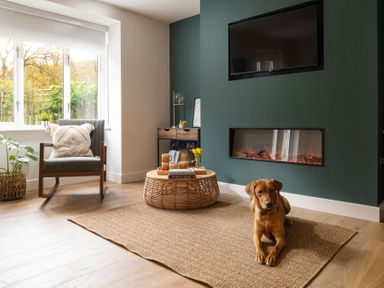 A living room with a dog on a rug a coffee table a rocking chair and a fireplace at Hebog in Beddgelert