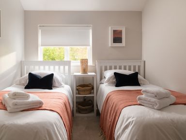 A bedroom with two single beds and a window between at Hebog in Beddgelert