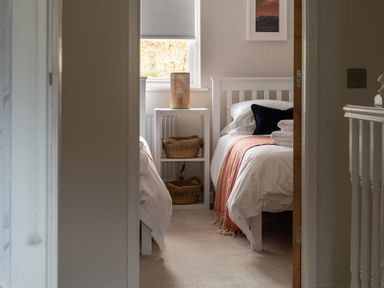 A bedroom with two single beds a nightstand with baskets and a lamp at Hebog in Beddgelert