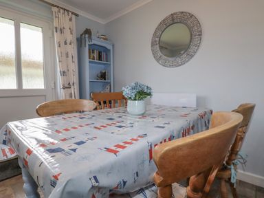 A dining room with a table covered by a patterned plastic tablecloth and wooden chairs at Merryfield Lodge in Rosecraddoc near Liskeard