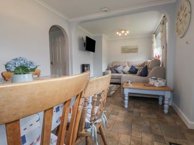 A living room with wooden chairs around a table and a sofa with cushions at Merryfield Lodge Rosecraddoc near Liskeard