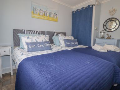 A bedroom with two single beds with blue bedding and pillows with sun sea sleep text at Merryfield Lodge Rosecraddoc near Liskeard