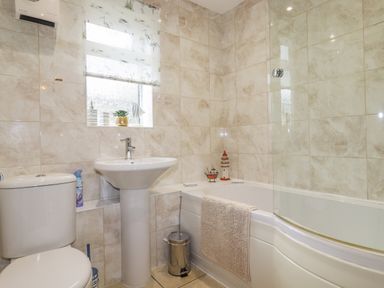 A bathroom with a toilet sink bathtub and a window with a floral blind at Merryfield Lodge Rosecraddoc near Liskeard