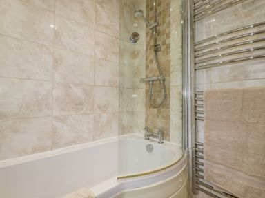A bathroom with a bathtub shower combination and a towel on a heated rail at Merryfield Lodge in Rosecraddoc near Liskeard