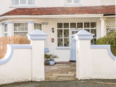 A front entrance of a house with a tiled pathway white walls and a blue door at 3 St Davids Place in Llandudno