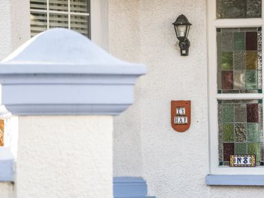 A house exterior with a window having stained glass panels and a sign with number 3 and Ty Haf plaque next to a black outdoor light fitting at 3 St Davids Place in Llandudno