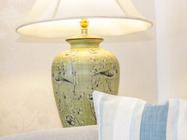 A table lamp with floral and bird design next to a striped cushion on a sofa at 3 St Davids Place in Llandudno