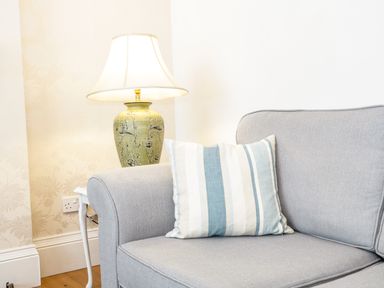A gray sofa with a striped cushion next to a side table with a lamp at 3 St Davids Place in Llandudno