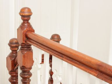 A wooden staircase railing with turned balusters and white decorative panels at 3 St Davids Place in Llandudno