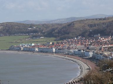 A curved coastline with a promenade and buildings along the shore at 3 St Davids Place in Llandudno