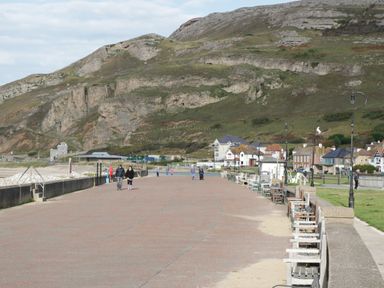 A promenade with benches and lamp posts near houses and hills at 3 St Davids Place in Llandudno