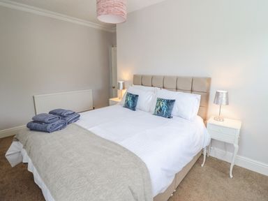 A bedroom with a double bed two bedside tables with lamps and folded towels on the bed at 24 Cadnant Park in Conwy