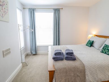 A bedroom with a bed with towels on it blue curtains and a clothes rack at 24 Cadnant Park in Conwy