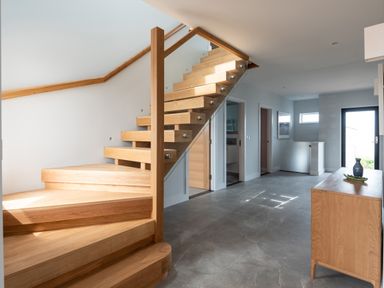 A hallway with wooden stairs glass railing and wooden sideboard with vase at The Old Coastguard Lookout in Port Isaac