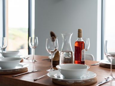 A dining table set with wine glasses bowls cutlery a bottle of wine and a carafe of water at The Old Coastguard Lookout in Port Isaac