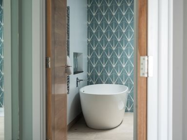 A bathroom with a freestanding bathtub and geometric patterned wall at The Old Coastguard Lookout in Port Isaac