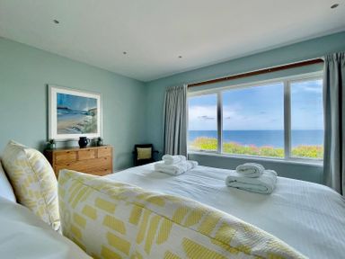 A bedroom with a large bed facing a window with an ocean view at The Old Coastguard Lookout in Port Isaac