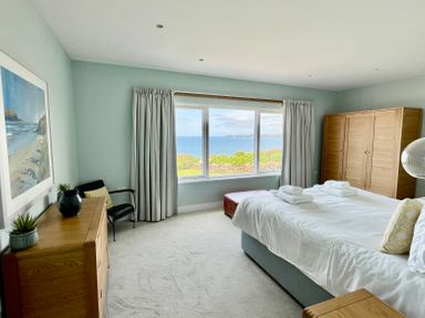 A bedroom with a bed and towels by a large window with ocean view at The Old Coastguard Lookout in Port Isaac