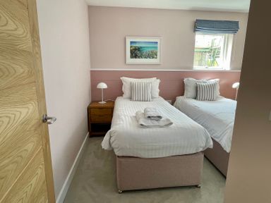 A bedroom with two single beds bedside tables lamps and a window at The Old Coastguard Lookout in Port Isaac
