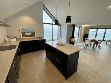 A kitchen with a view of the sea and a dining area at The Old Coastguard Lookout Port Isaac