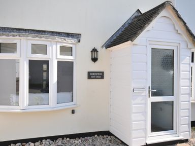 An exterior view of Shrimper's Cottage featuring a sign and windows in Tredrizzick near St Minver