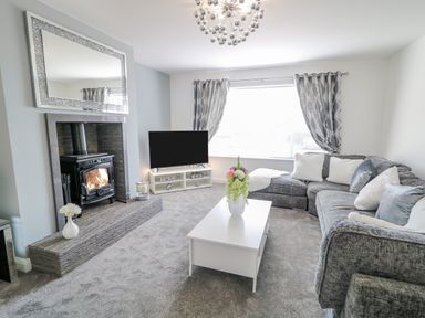 A living room with sectional sofa coffee table and fireplace at SJs Cottage in Castlerock