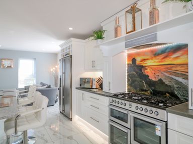 A kitchen with a marble floor white cabinets a large stove and a breakfast bar with chairs at SJs Cottage in Castlerock