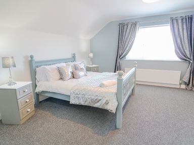 A bedroom with a bed pillows bedside tables lamps and curtains at SJs Cottage in Castlerock