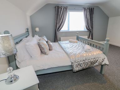 A bedroom with a bed pillows lamps and curtains at SJs Cottage in Castlerock