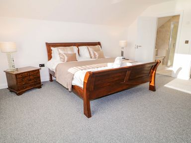 A bedroom with a wooden double bed bedside tables lamps and an ensuite bathroom at SJs Cottage in Castlerock