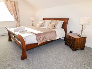 A bedroom with a wooden bed and bedside table with a lamp at SJs Cottage Castlerock