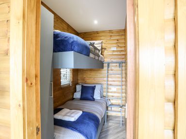 A small wooden bedroom with bunk beds and a ladder to the top bed at Hilltop Lodge in Corwen