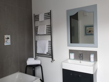 A bathroom with a sink cabinet mirror towel rack and a stool with towels at No.37 in Beverley
