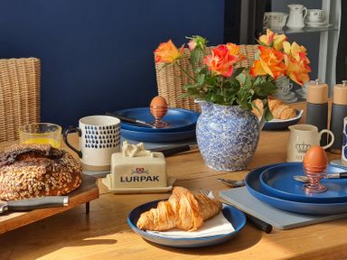 A dining table with croissants bread butter mugs and a vase of flowers at No.37 in Beverley
