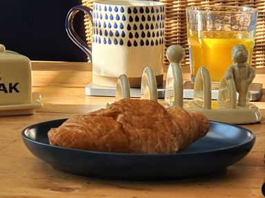 A croissant on a blue plate with a mug and a glass of orange juice on a wooden table at No.37 in Beverley