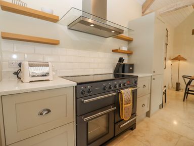 A kitchen with a stove oven toaster knife set shelves and cabinets at Hawthorn Barn Northleach