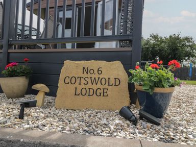 A sign stating No.6 Cotswold Lodge with flower pots in an outdoor area at The Cotswold Holiday Lodge Evesham