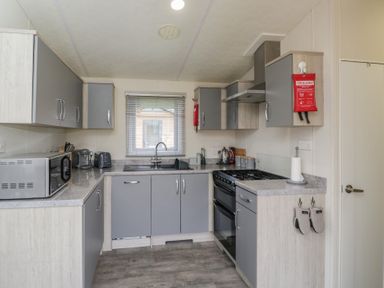 A kitchen with cabinets, sink, and appliances at The Cotswold Holiday Lodge in Evesham