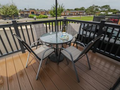 A table with chairs and drinks on a patio at The Cotswold Holiday Lodge in Evesham