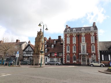 A street view with a historic clock tower and buildings including The Castle Hotel at Dove Cottage in Ruthin