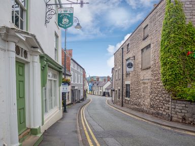A narrow street with buildings on both sides and signs hanging outside at Dove Cottage in Ruthin