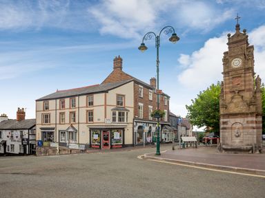 A street view with a clock tower shop buildings and a lamppost in a town