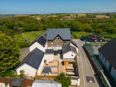 An aerial view of a house with a slate roof and courtyard next to a playground and green fields at Teifi Villa in St Dogmaels