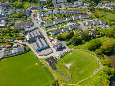 An aerial view of a small town with houses roads green fields and a playground near a river
